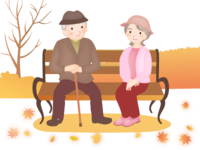 An elderly couple sitting on a bench in an autumn park